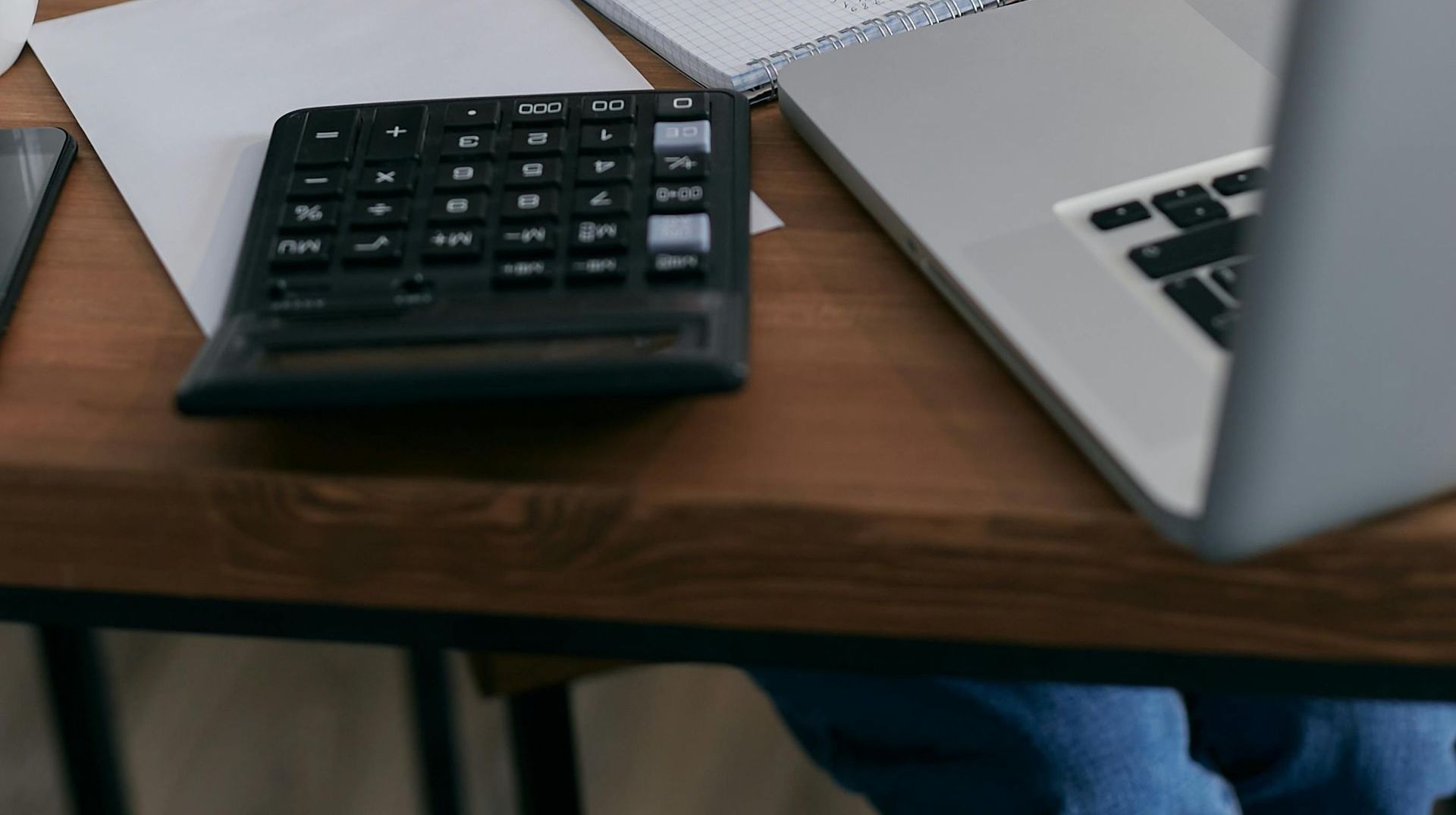 A person is sitting at a desk with a laptop and a calculator.