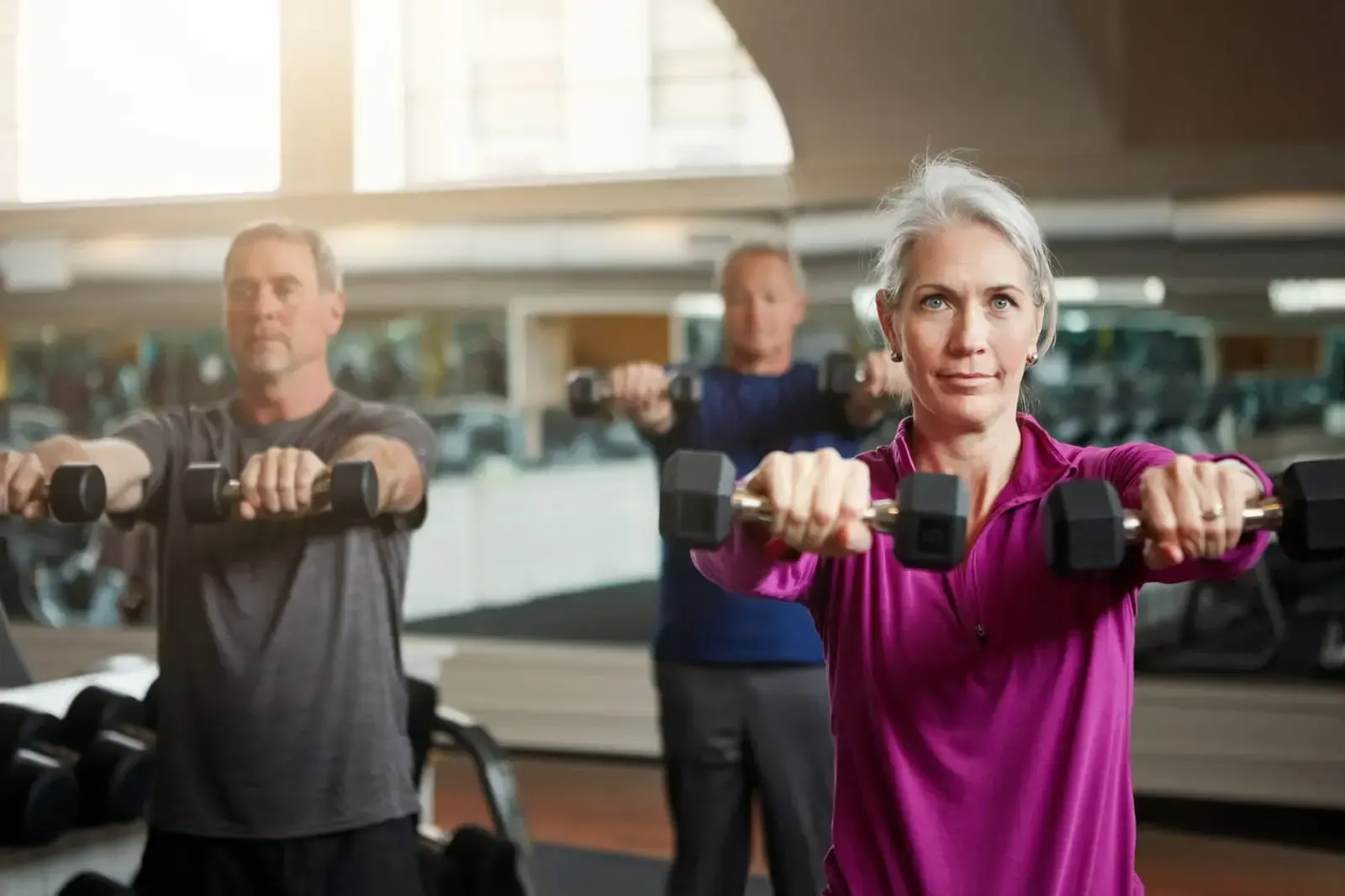 A group of people are lifting dumbbells in a gym.