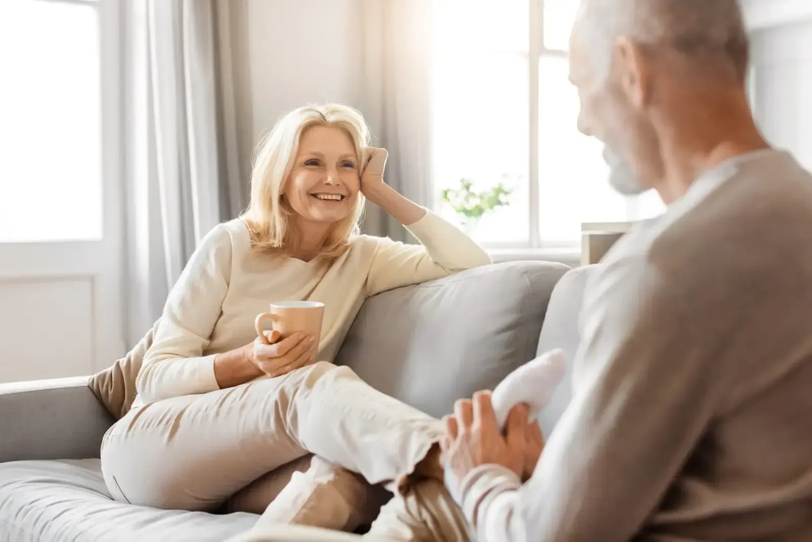 A man and a woman are sitting on a couch talking to each other.