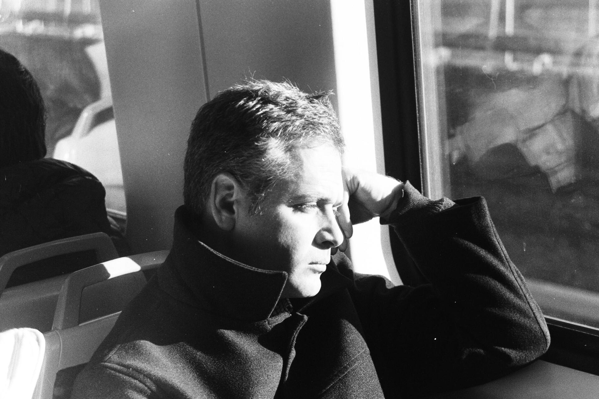 A man is sitting on a bus looking out the window.