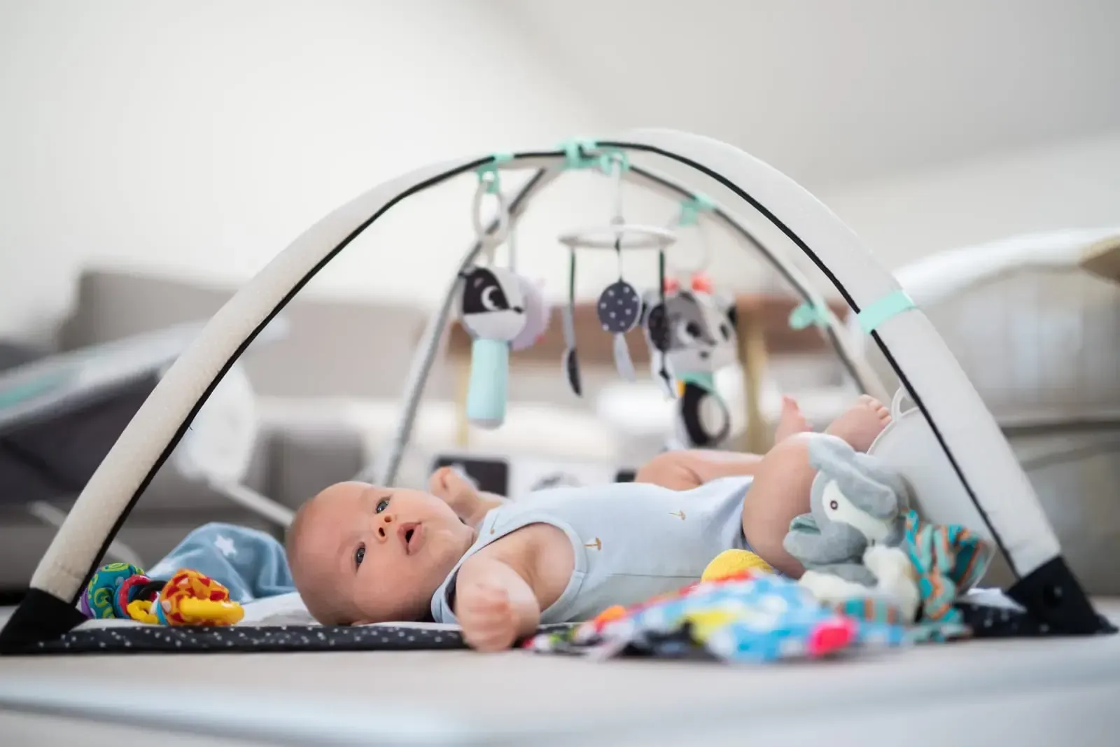 A baby is laying on a play mat with toys.