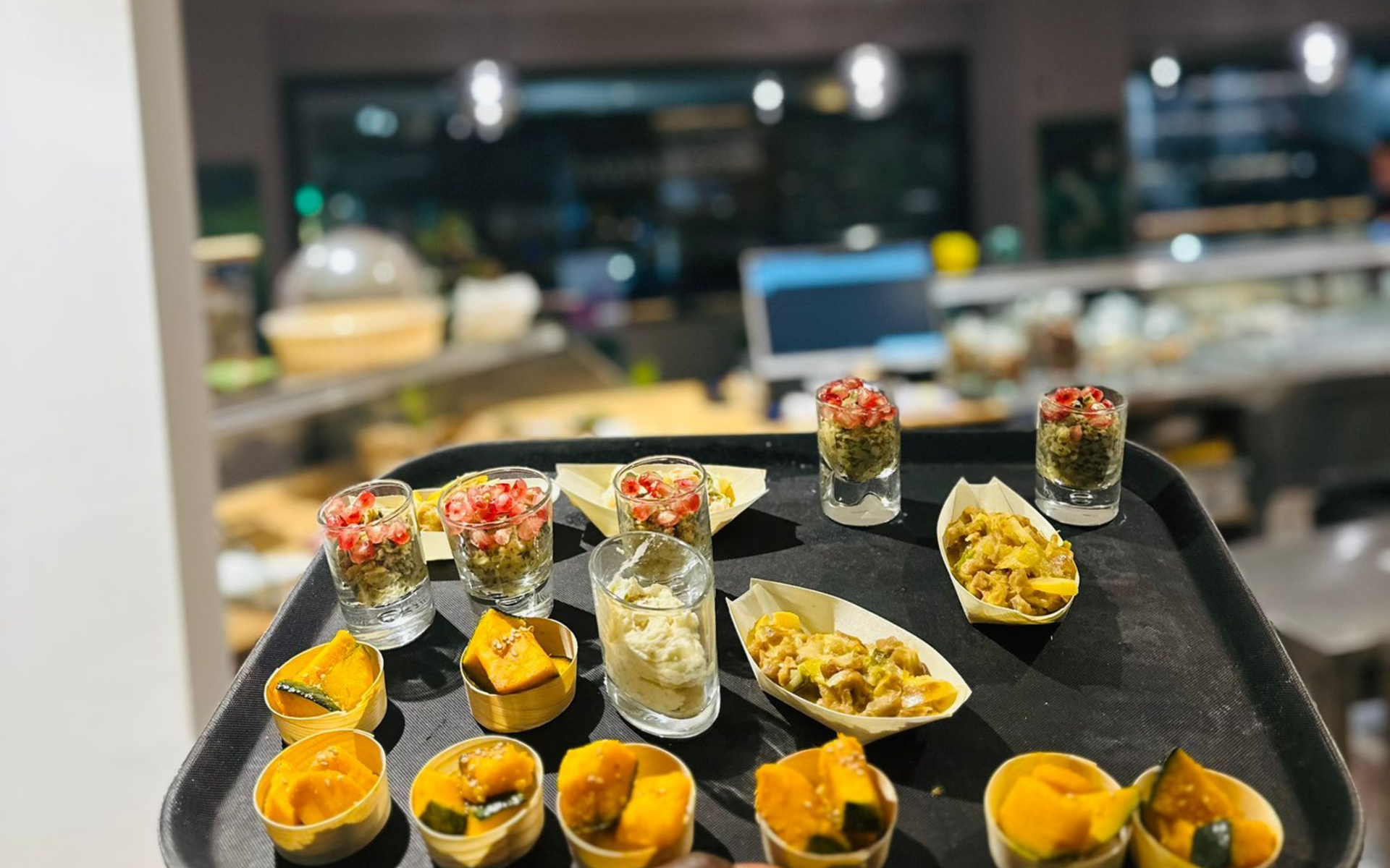 Vassoio di antipasti: bicchierini colorati e bicchierini da shot pieni di stuzzichini vari, ambientazione da ristorante.