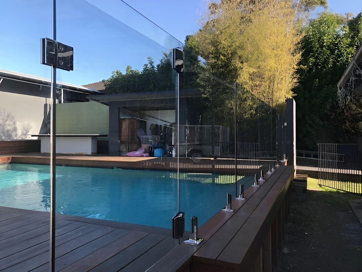 A Swimming Pool With A Glass Fence Around It — Master Glass & Glazing In Eleebana, NSW