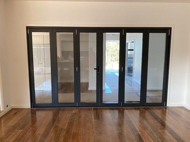 An Empty Room With Hardwood Floors And Sliding Glass Doors — Master Glass & Glazing In Mayfield, NSW