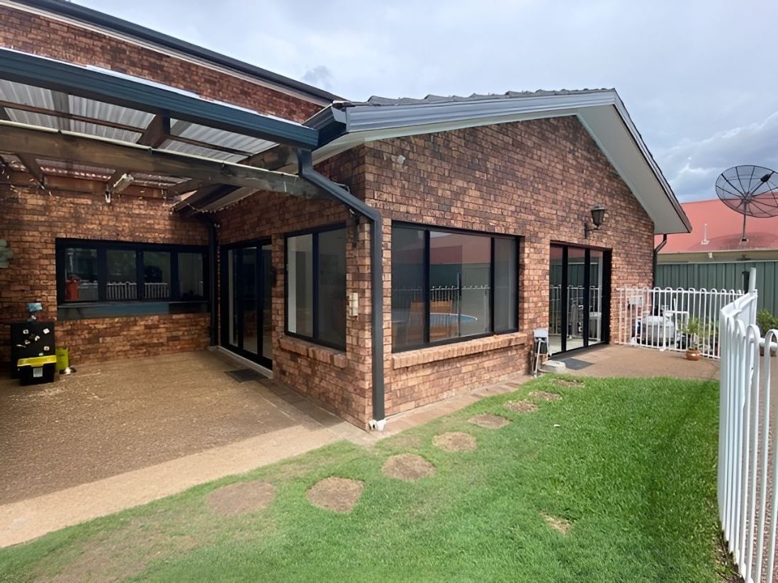 A Brick House With A Lot Of Windows And A Lawn In Front Of It — Master Glass & Glazing In Toronto, NSW