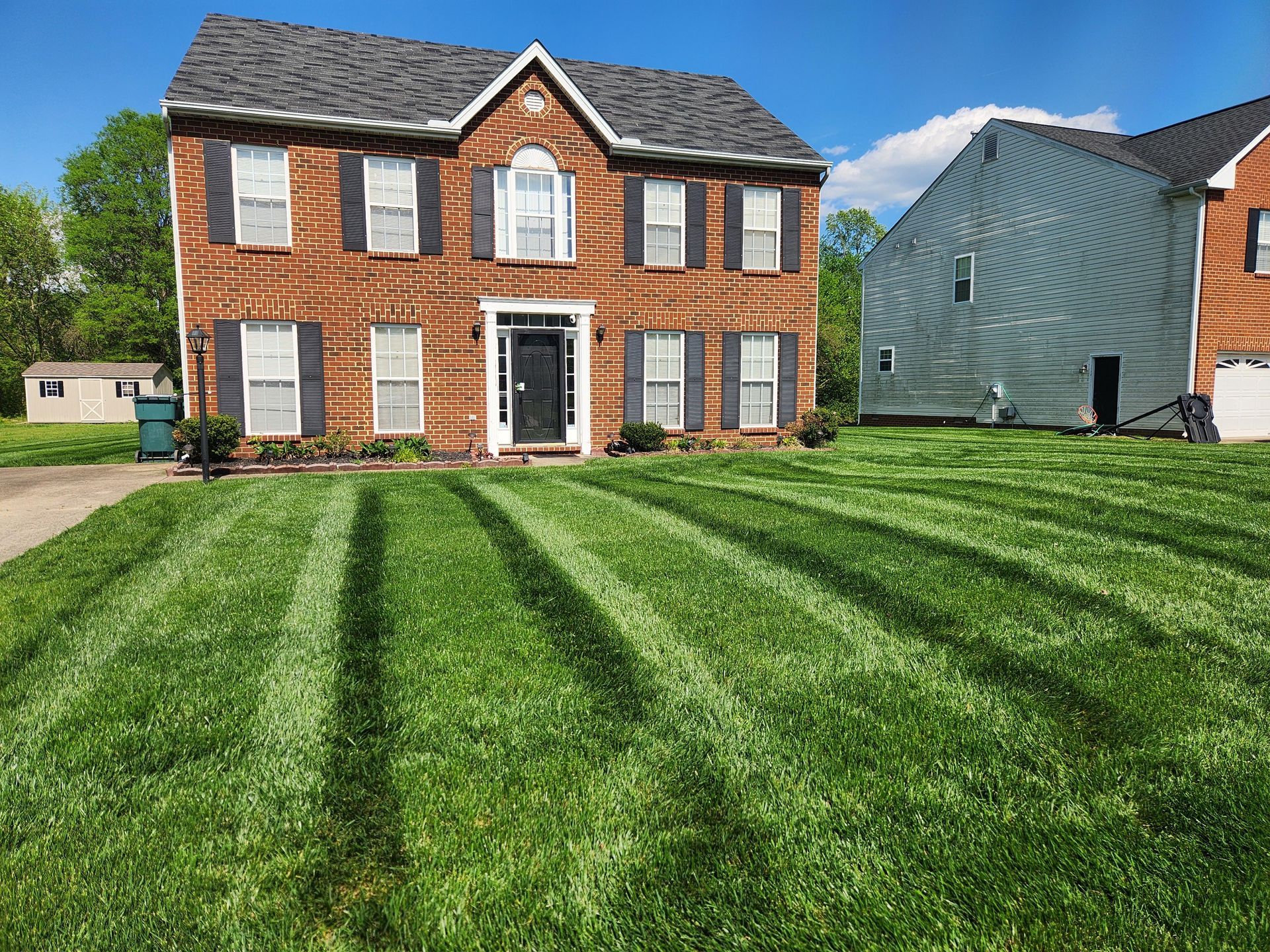 A large brick house with a lush green lawn in front of it.