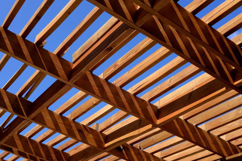 Wooden pergola with a blue sky visible through the beams.