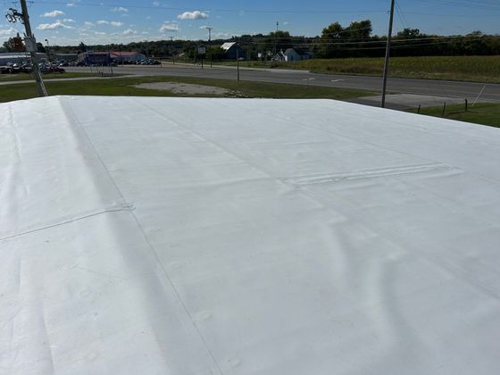 A large white tarp is sitting on top of a roof.