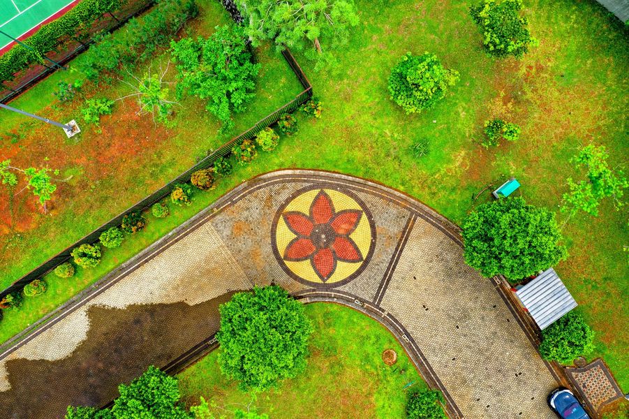An aerial view of a park with a flower design on the sidewalk.