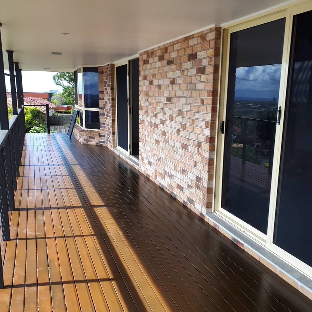 A Brick Building With A Wooden Deck And Sliding Glass Doors — Pottsville Carpentry and Home Maintenance In Pottsville, NSW