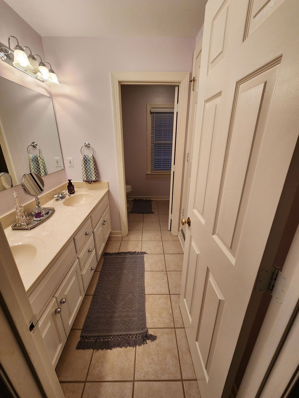 A bathroom with two sinks , a mirror and a window.