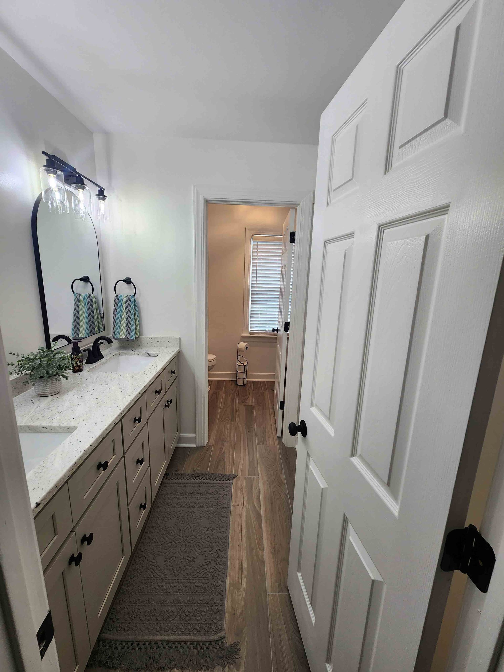 A bathroom with two sinks , a mirror , and hardwood floors.