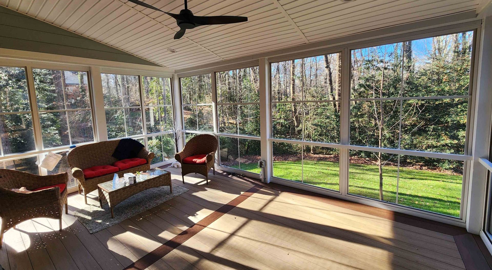 A screened in porch with furniture and a ceiling fan.
