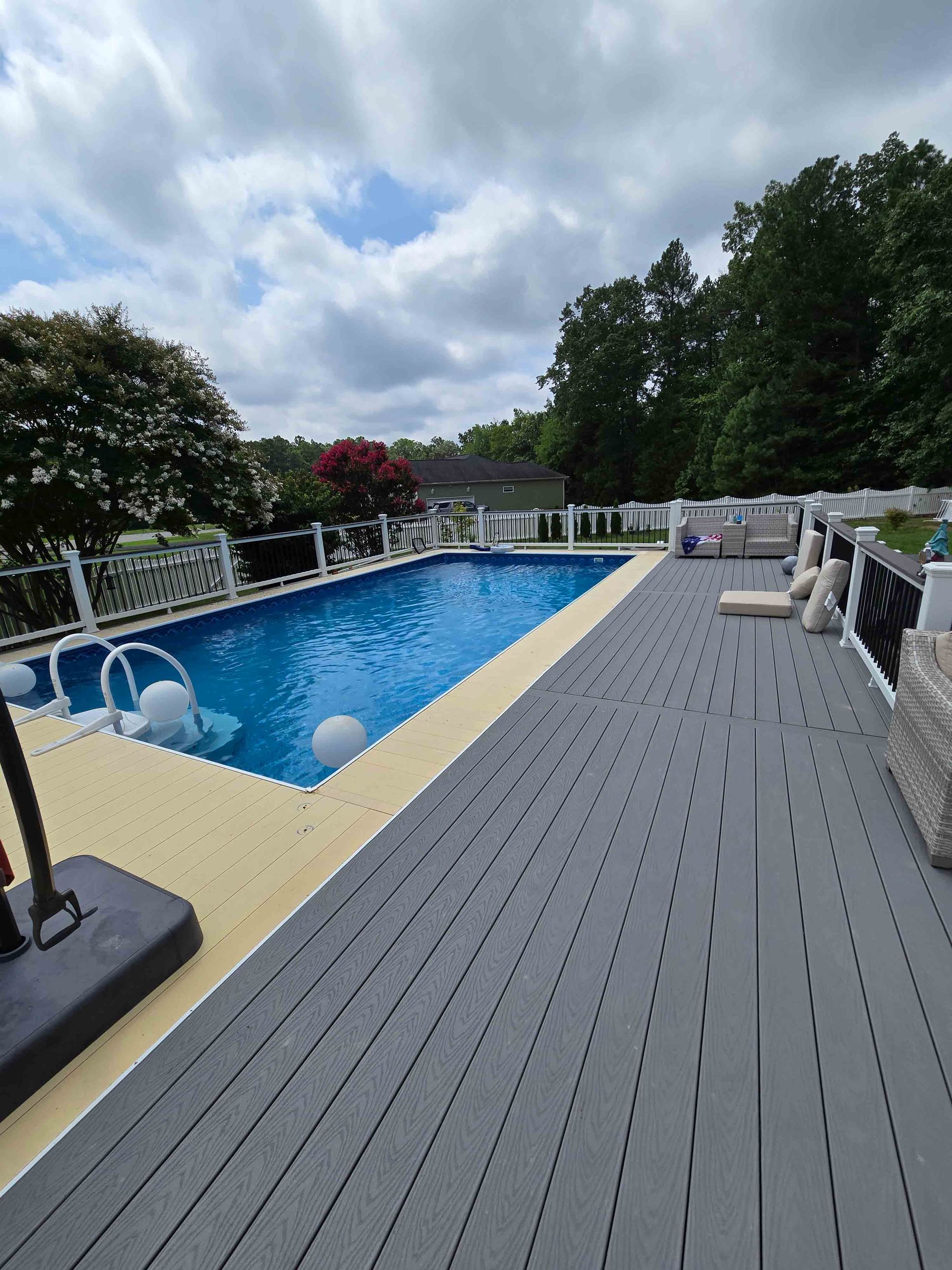 A large swimming pool is surrounded by a gray deck.