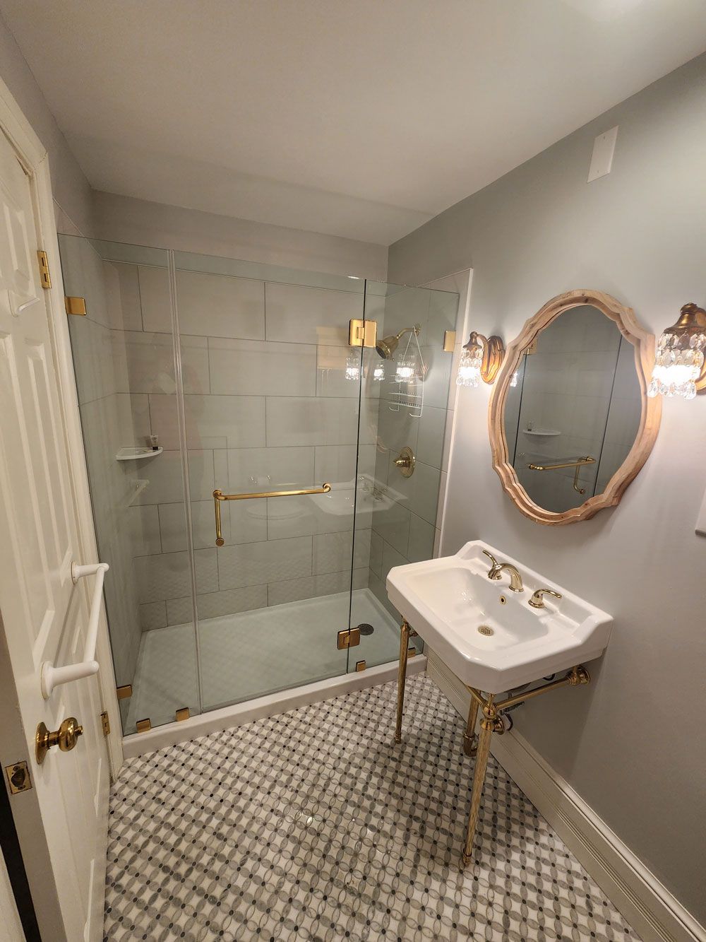 A bathroom with a sink , mirror and walk in shower.