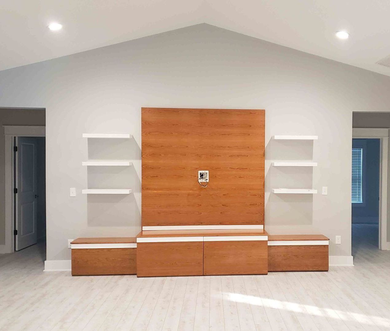 A living room with a wooden entertainment center and shelves.