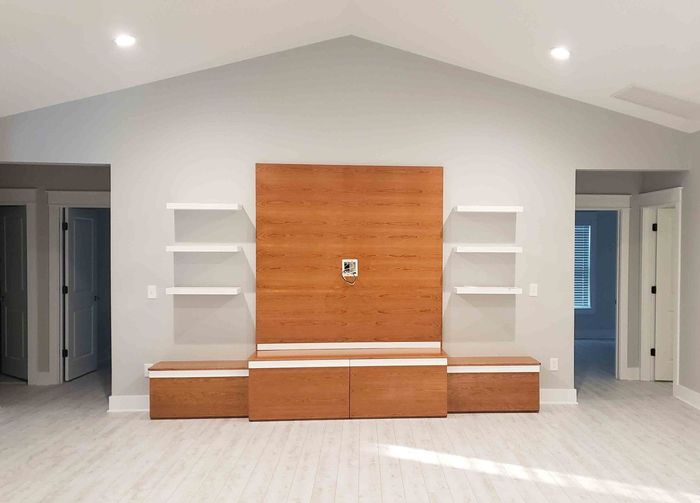 An empty living room with a wooden entertainment center and shelves.