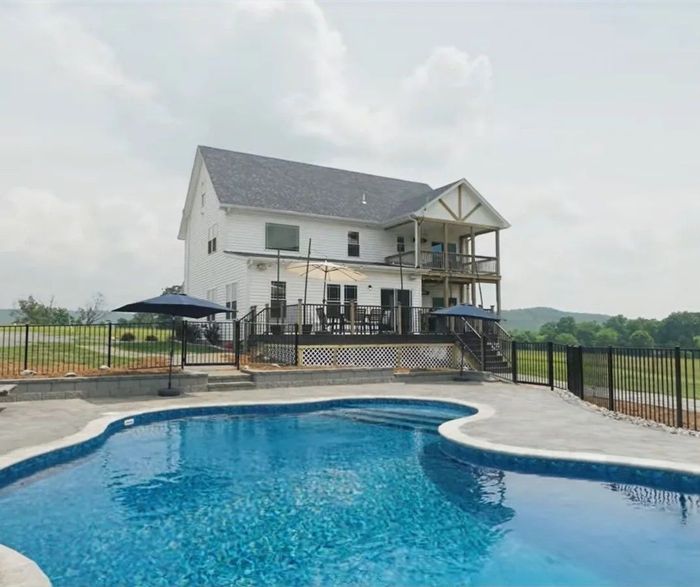 A large white house with a large swimming pool in front of it.