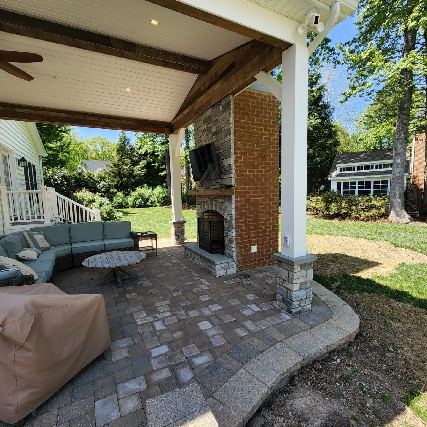 A patio with a sectional couch and a fireplace