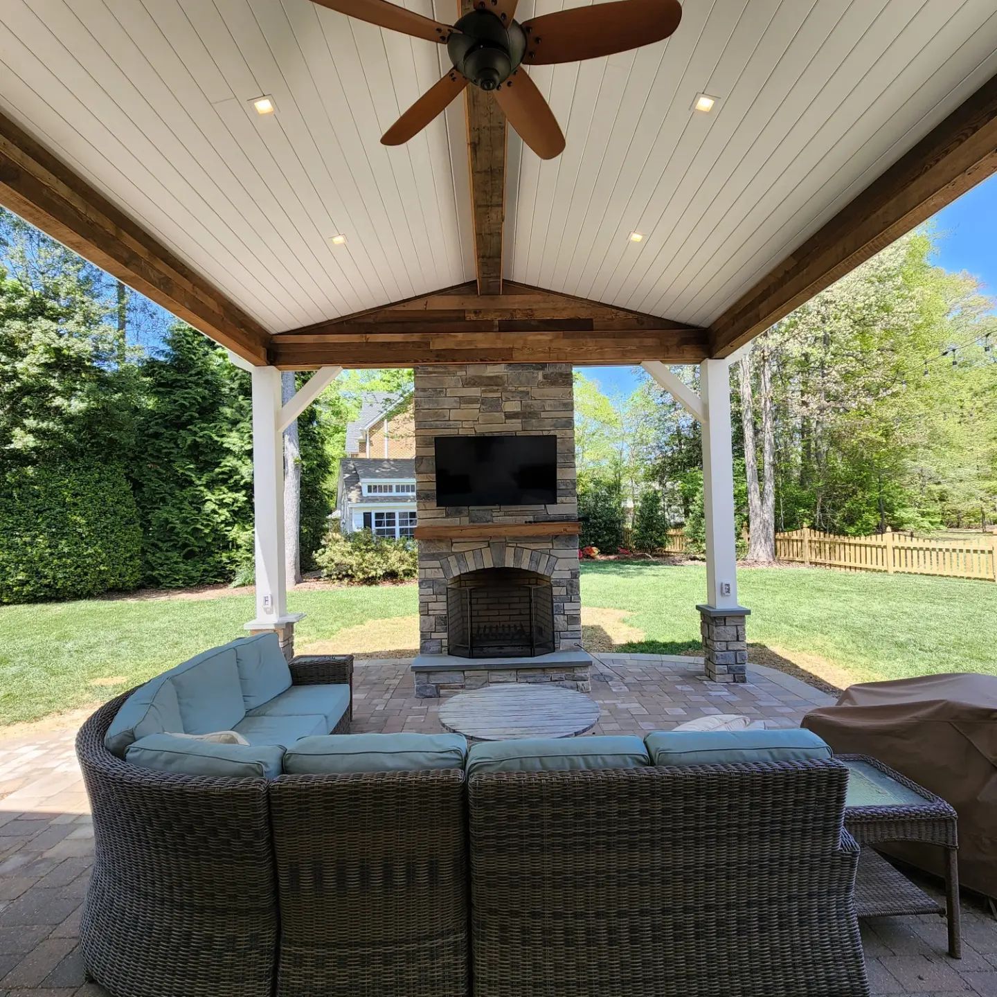 A patio with a fireplace and a ceiling fan