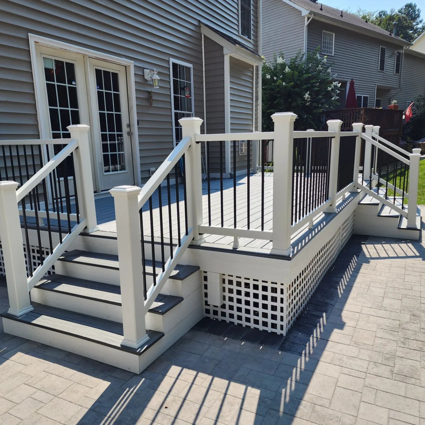 A white deck with black railing and stairs in front of a house
