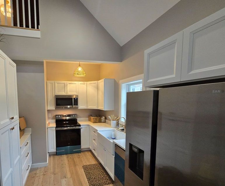 A kitchen with stainless steel appliances and white cabinets.