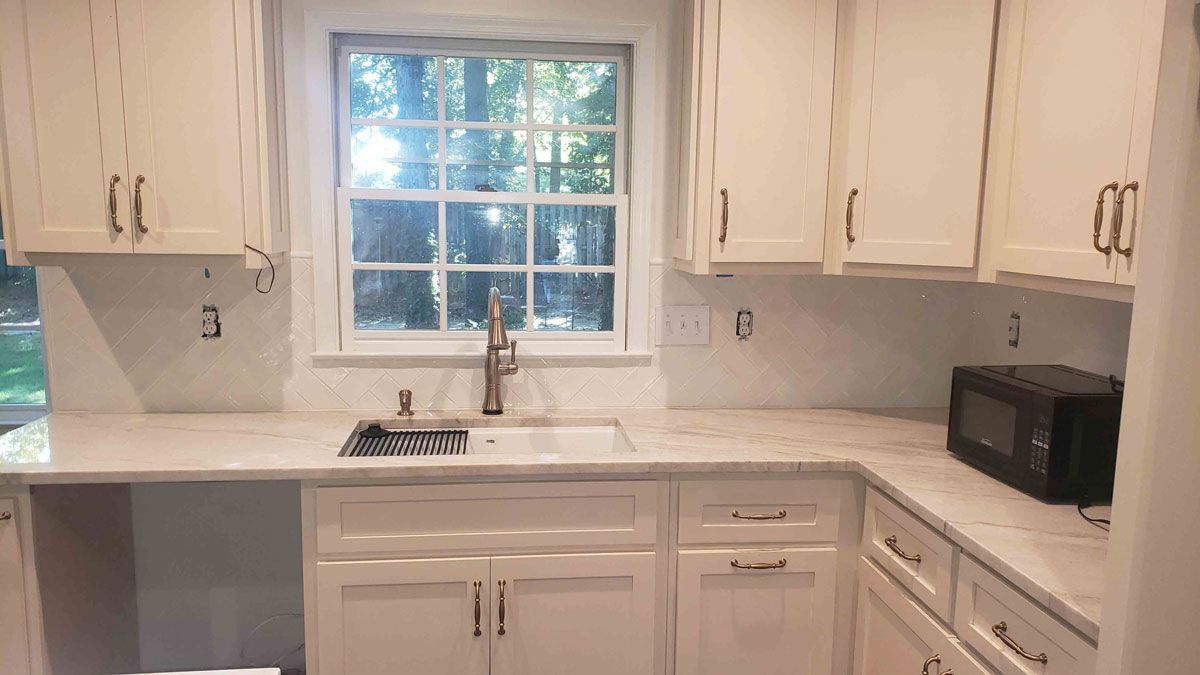 An aerial view of a kitchen with white cabinets and granite counter tops.
