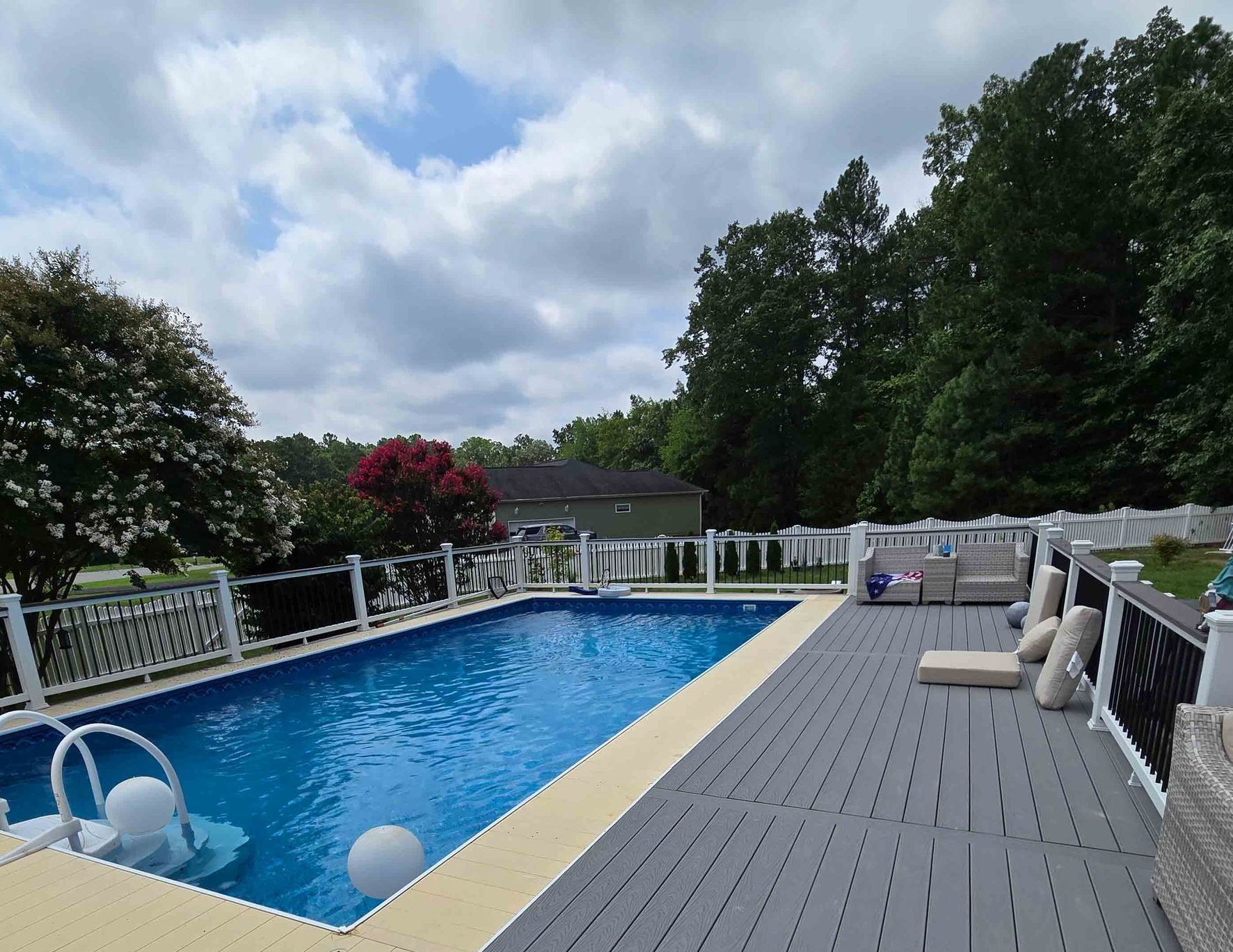 A large swimming pool surrounded by trees and a deck