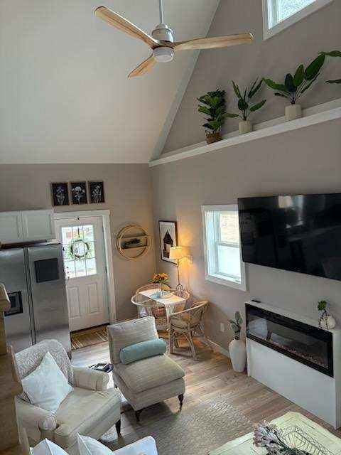 A living room with a ceiling fan and a flat screen tv.