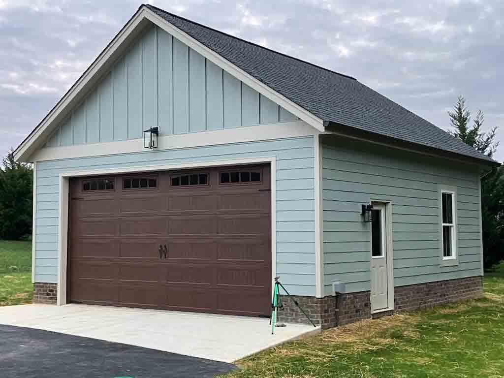 A blue garage with a brown garage door and a gray roof.