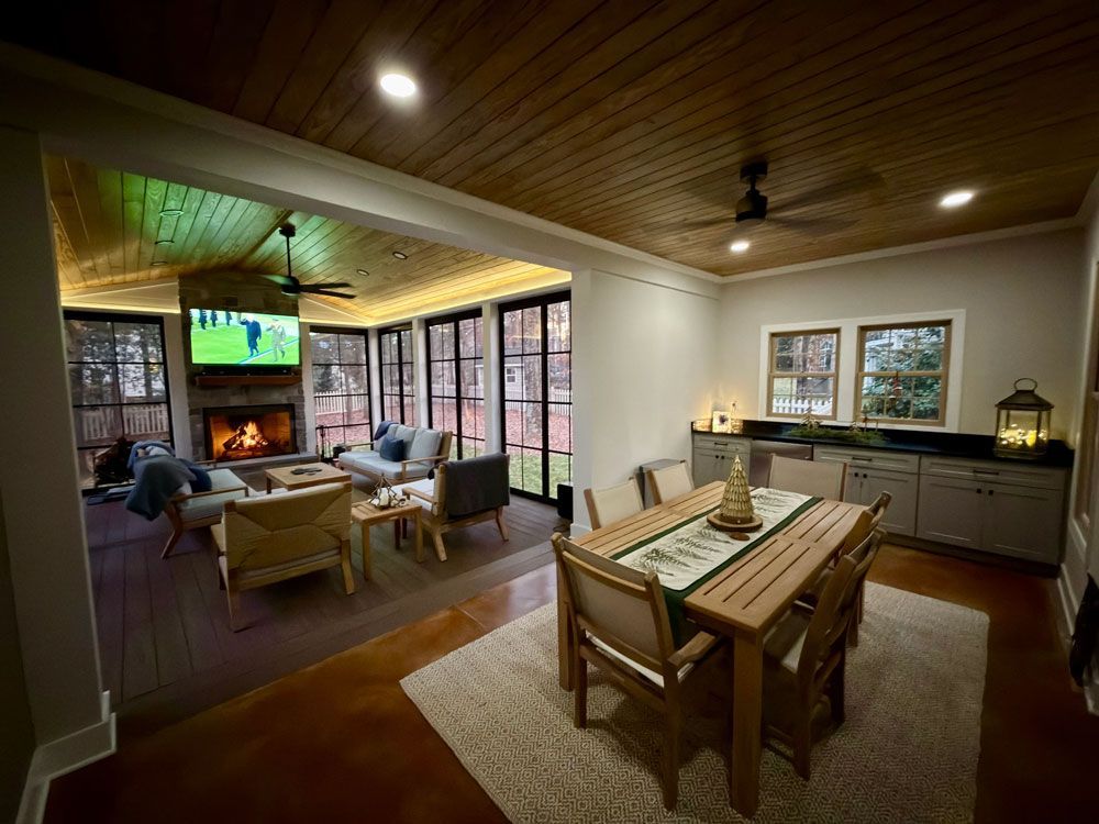 Cozy interior with fireplace, dining area, and outdoor seating. Brown wood, gray walls, warm lighting.