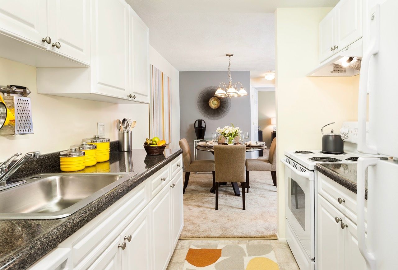 Open-concept kitchen with white cabinets, dark countertops, and a dining area.
