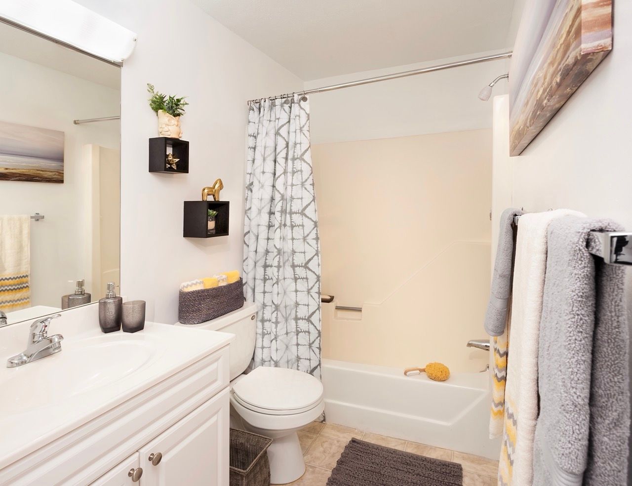 White bathroom with vanity, toilet, and bathtub with a patterned shower curtain.