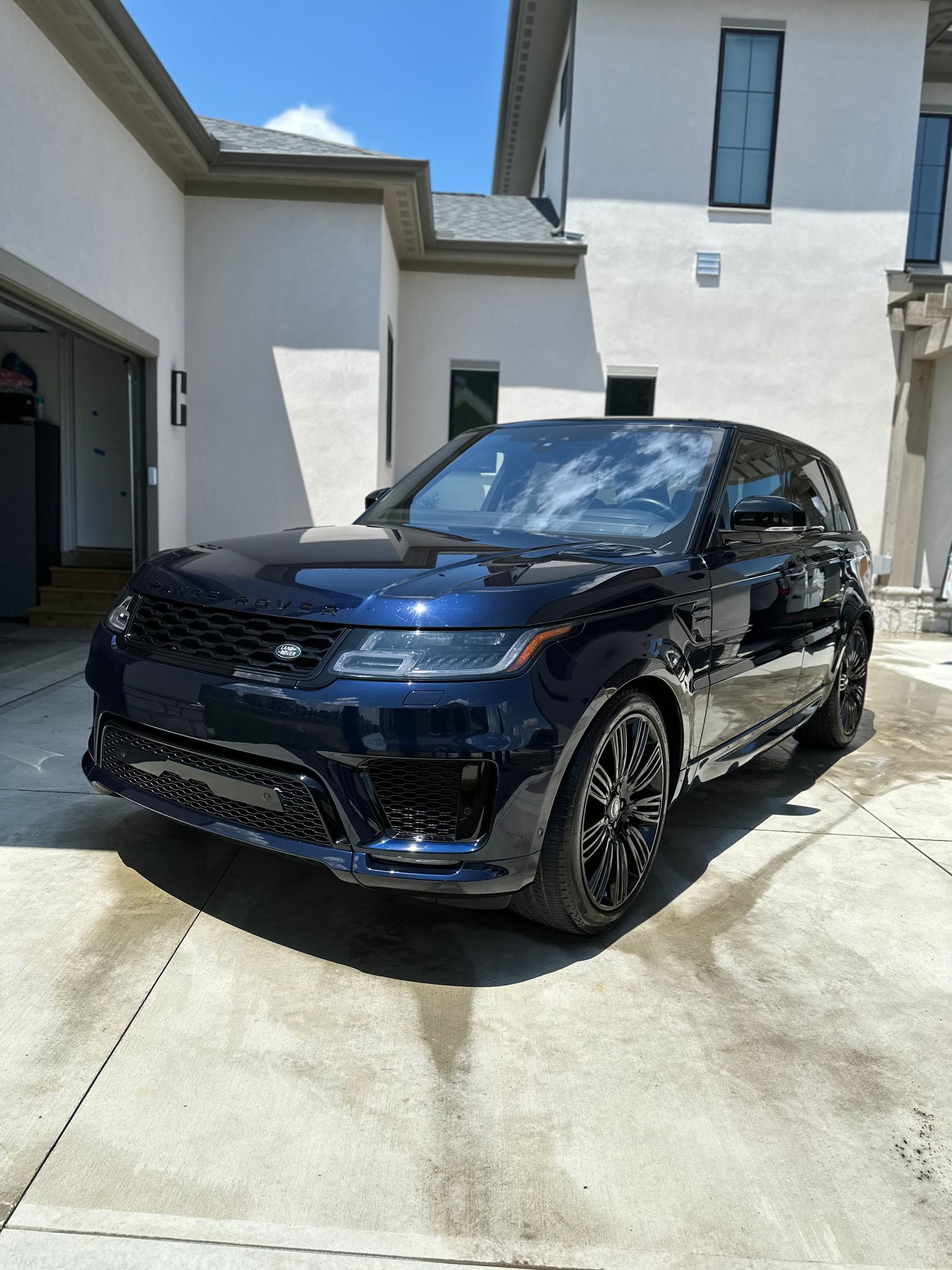 A black range rover sport is parked in front of a white house.