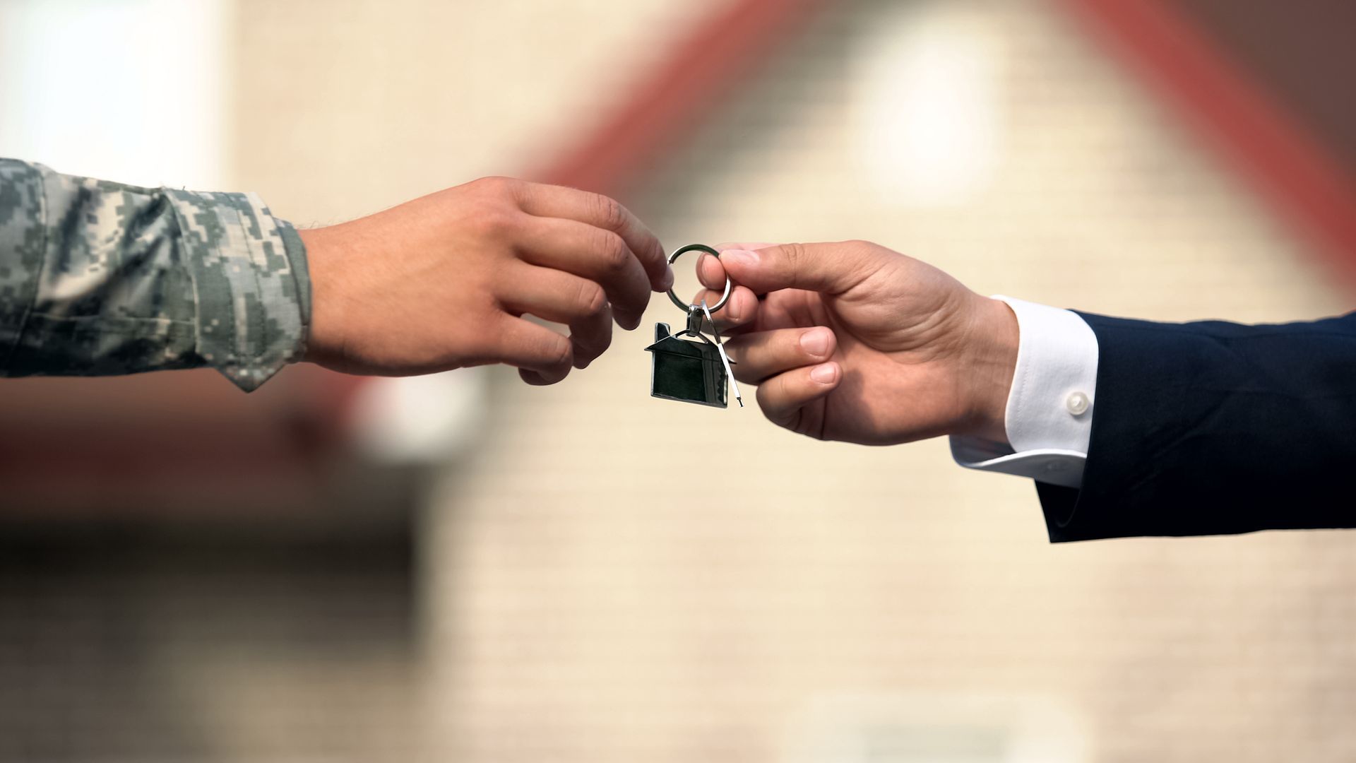 A soldier is handing a car key to a man in a suit.