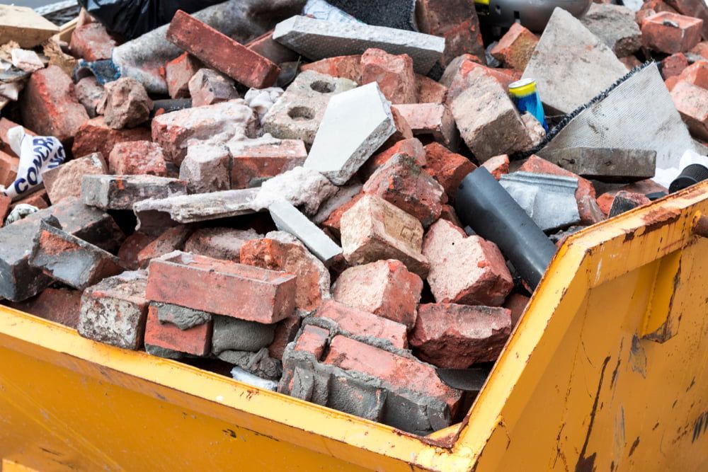 A Yellow Dumpster Filled with Bricks and Concrete — Central Coast Complete Demolition & Tree Service in Morisset, NSW