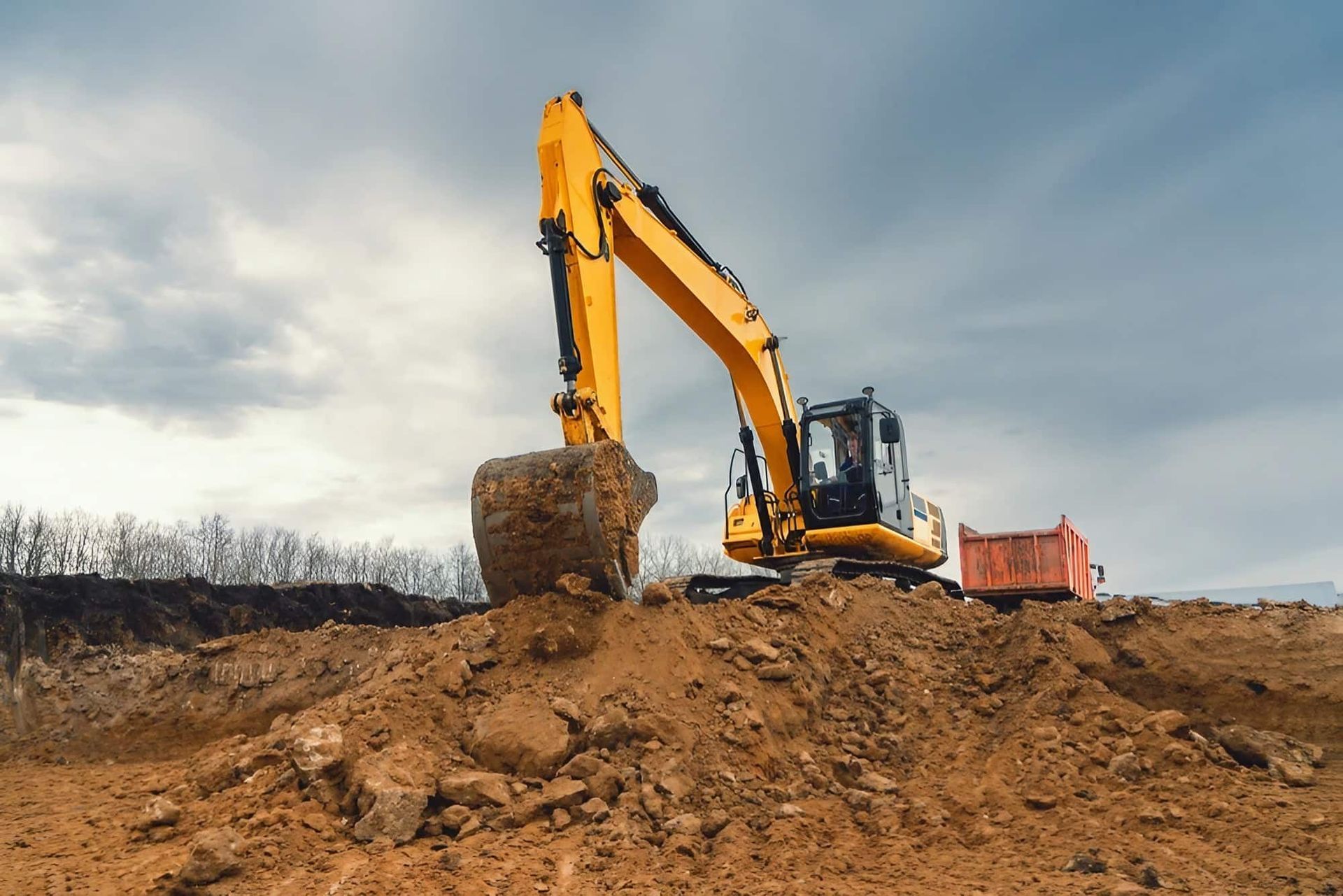 A Yellow Excavator Is Moving Dirt on A Construction Site — Central Coast Complete Demolition & Tree Service in Wyong, NSW