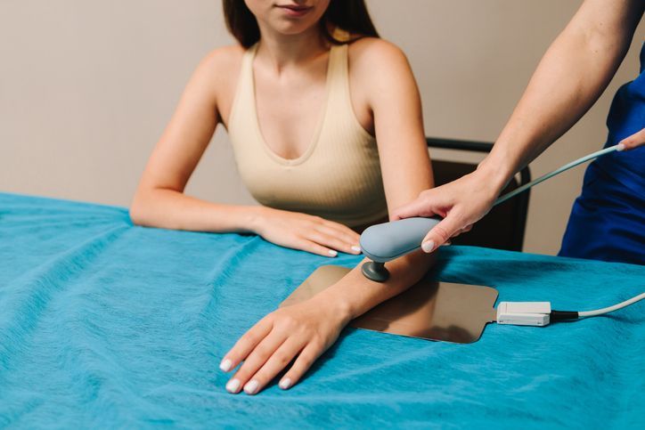 Una donna è seduta a un tavolo e si fa fare un massaggio al braccio.