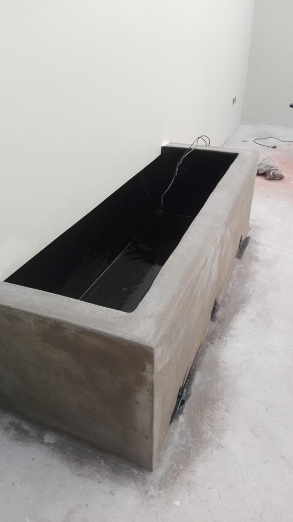 Macetero rectangular de madera con revestimiento negro en una habitación blanca, visto desde arriba y de lado.