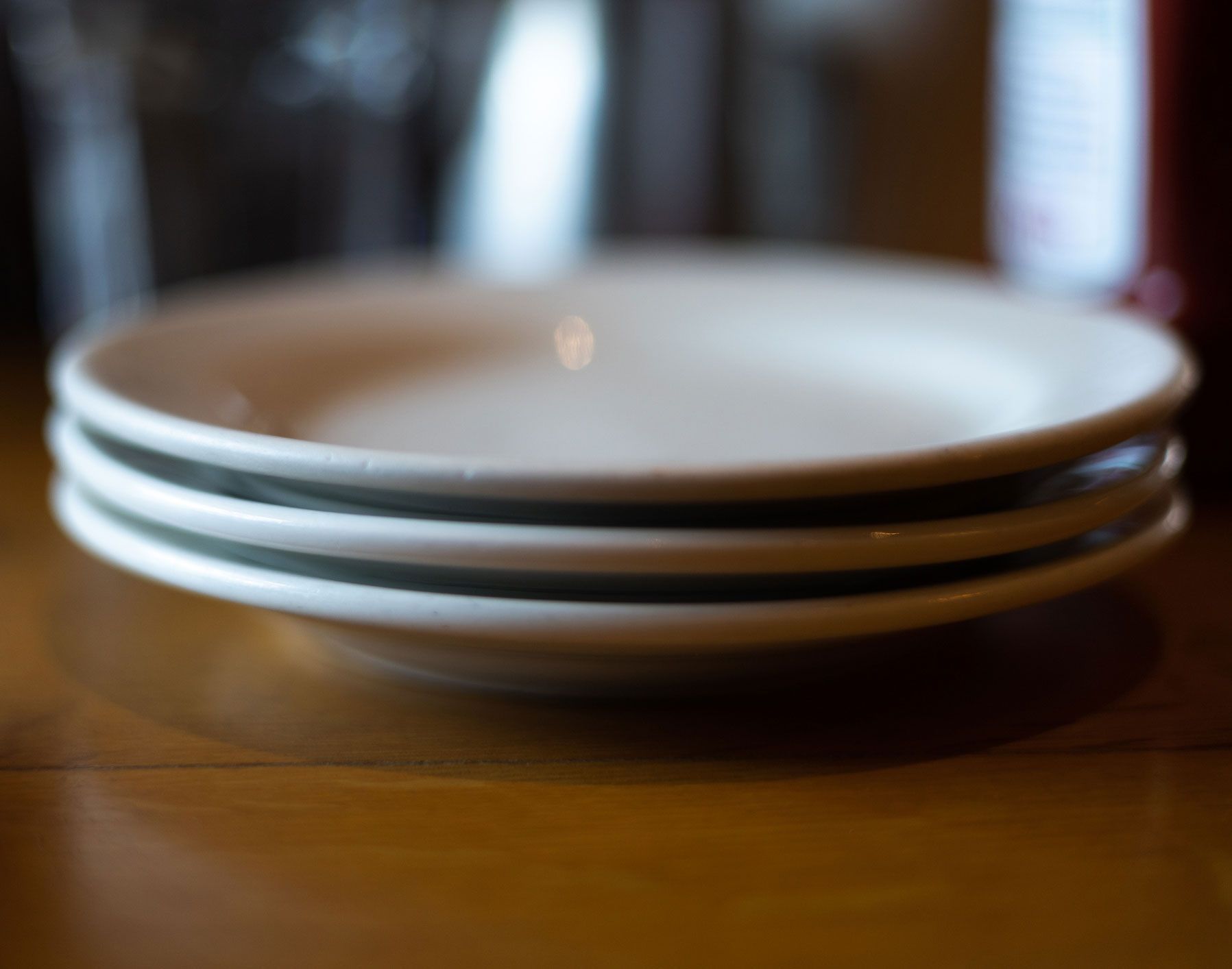 Three white plates are stacked on top of each other on a wooden table.