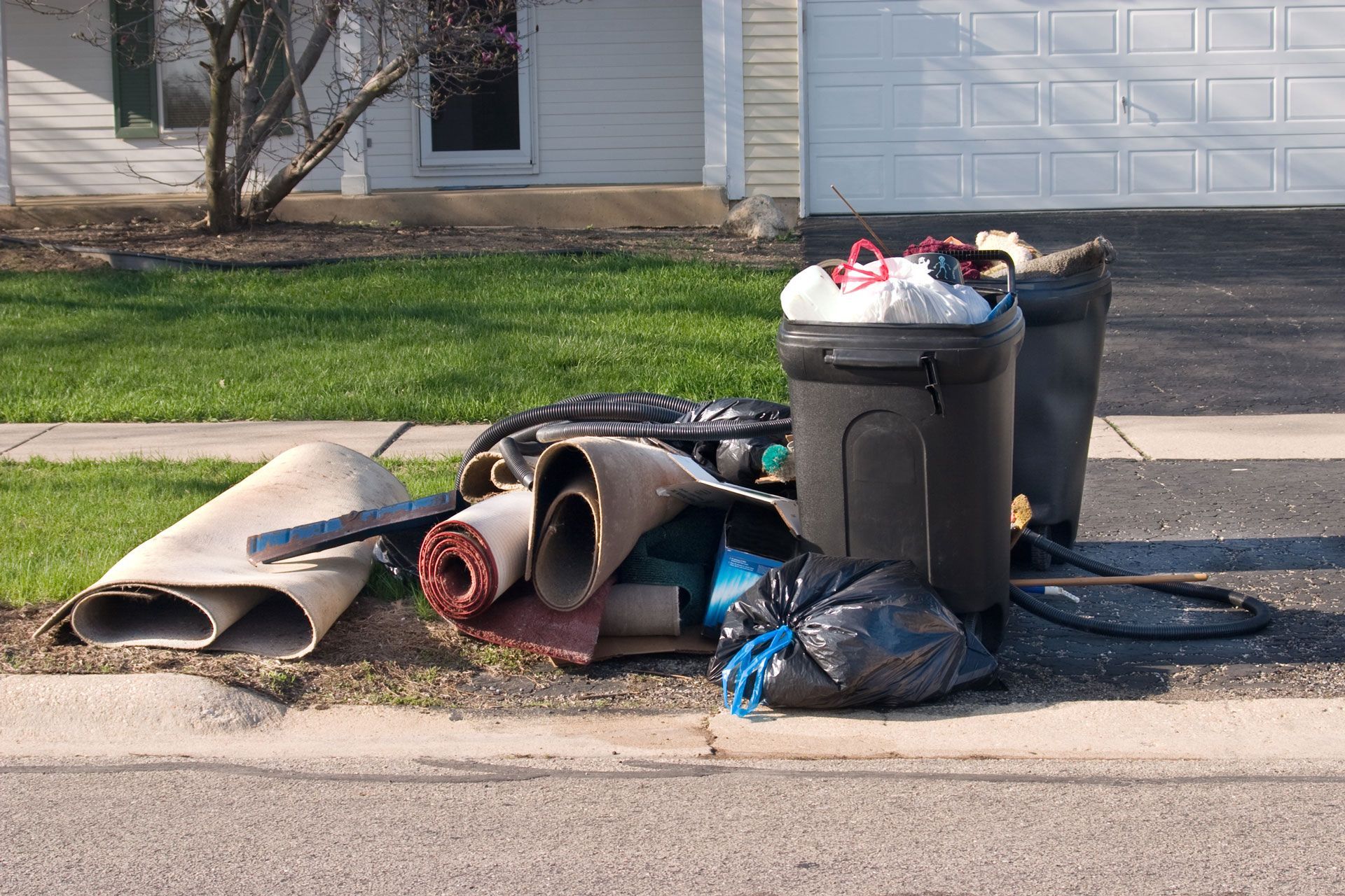 A pile of trash is sitting on the curb in front of a house.