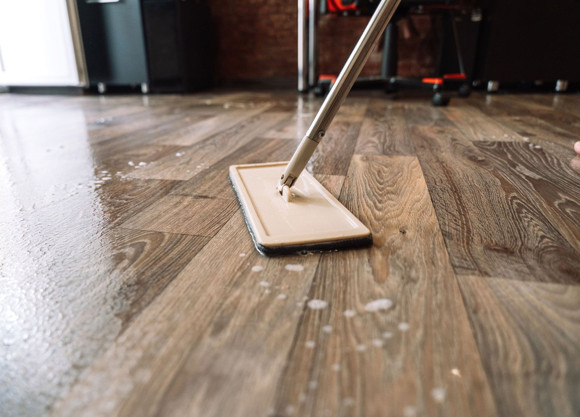 A person is mopping a wooden floor with a mop.