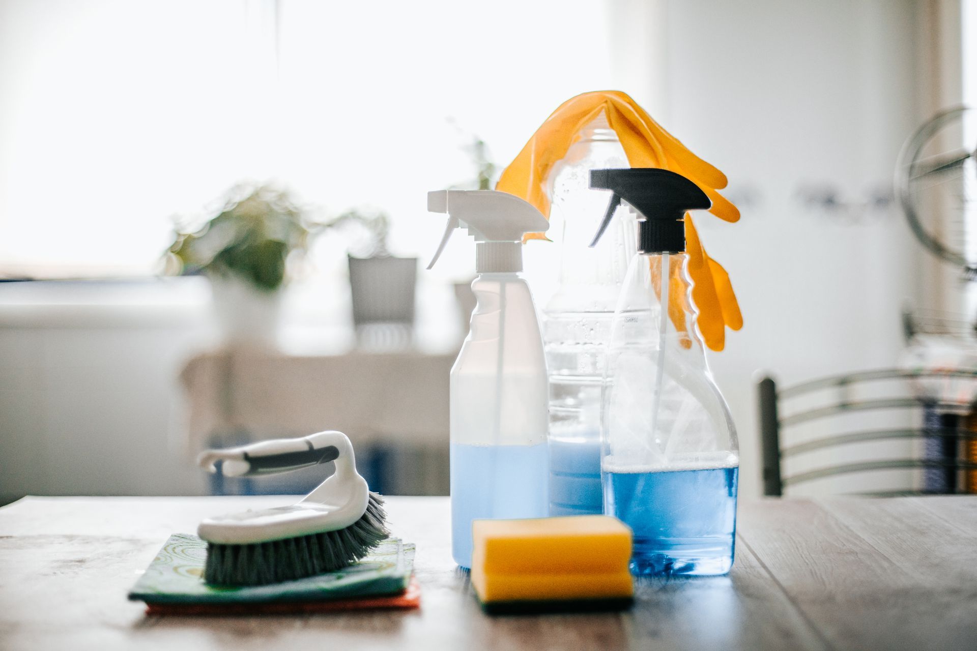 A table topped with spray bottles , sponges , brushes and gloves.