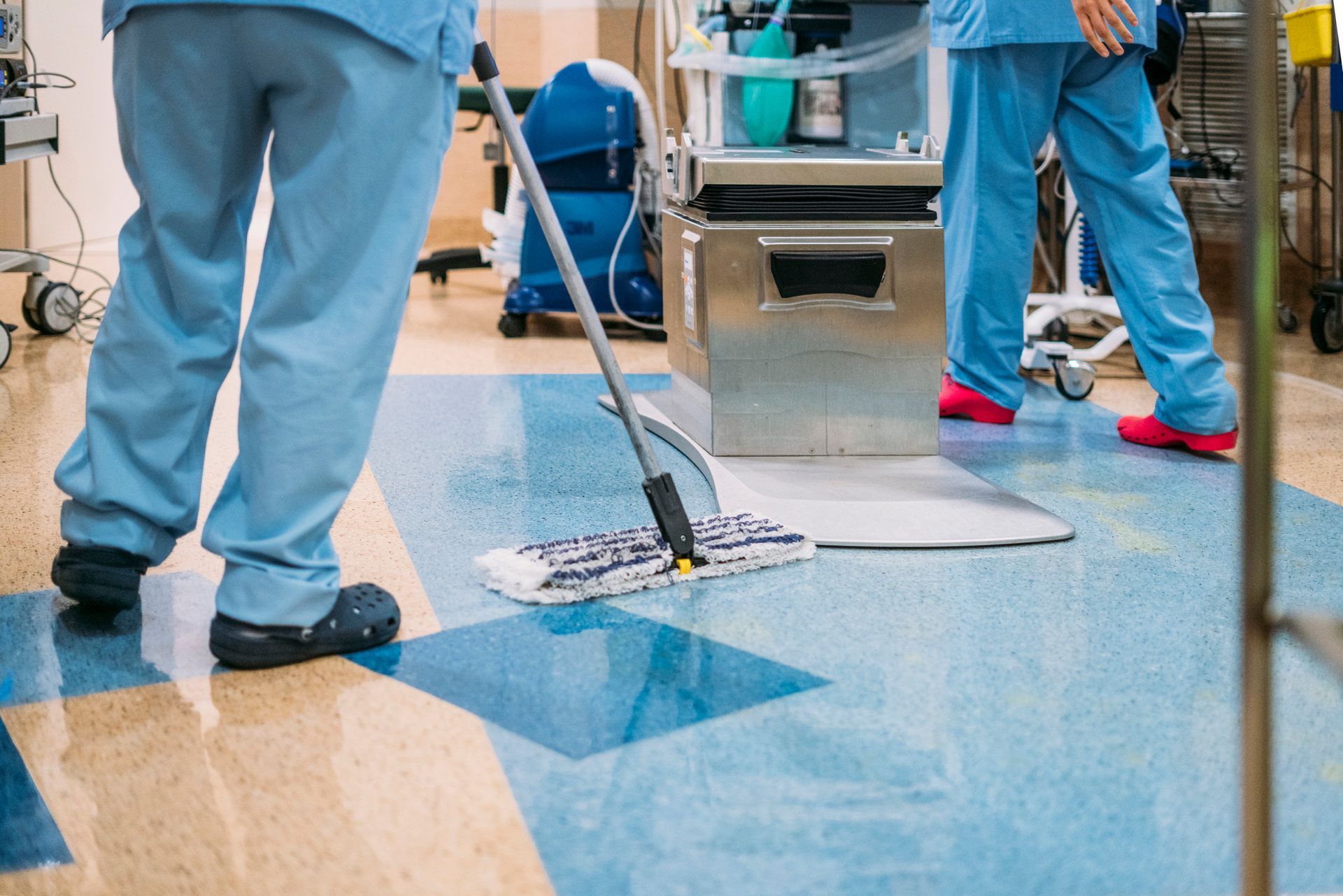 A group of nurses are cleaning a hospital floor with a mop.