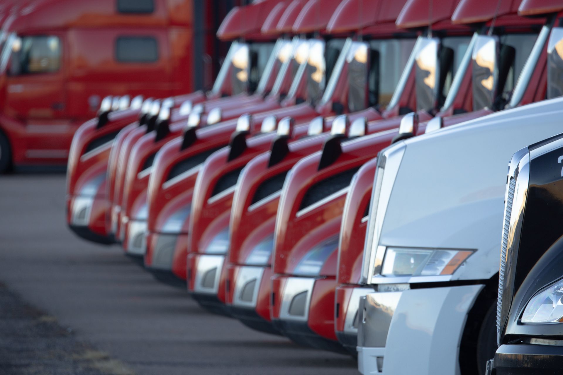 A row of red and white semi trucks are parked next to each other
