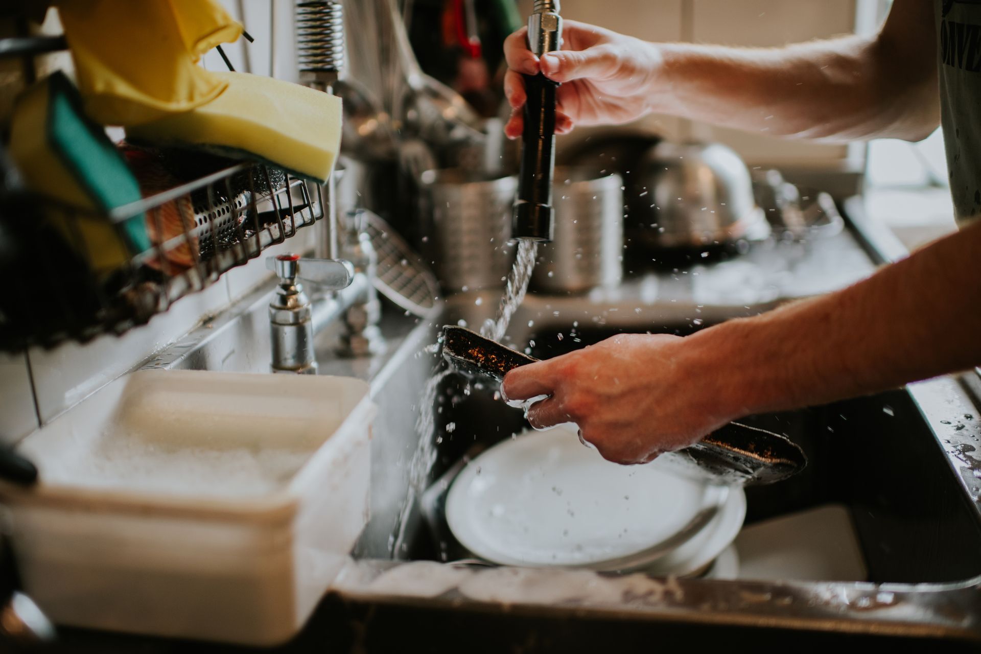 A person is washing dishes in a kitchen sink.