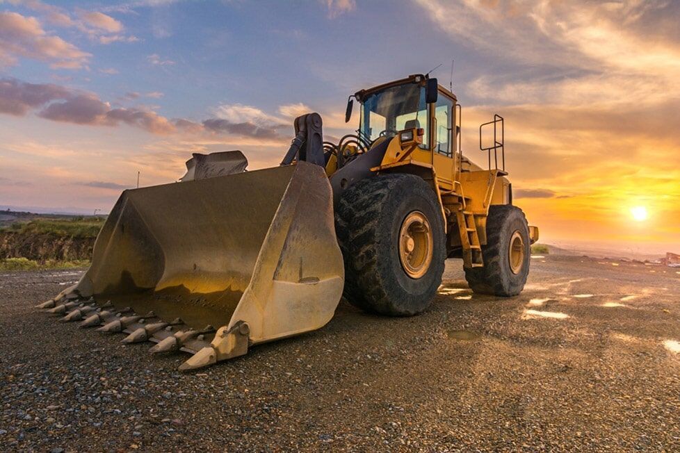 A Bulldozer Is Parked On The Side Of The Road At Sunset — Kset Engineering in Thornton, NSW
