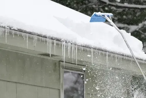 removing snow on the roof after a snowstorm
