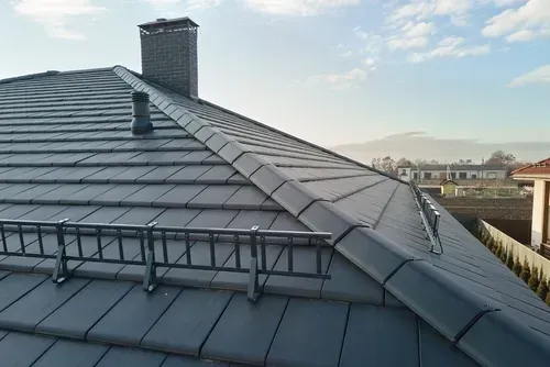 Close-up snow guard for safety in winter on the house roof top covered with ceramic shingles