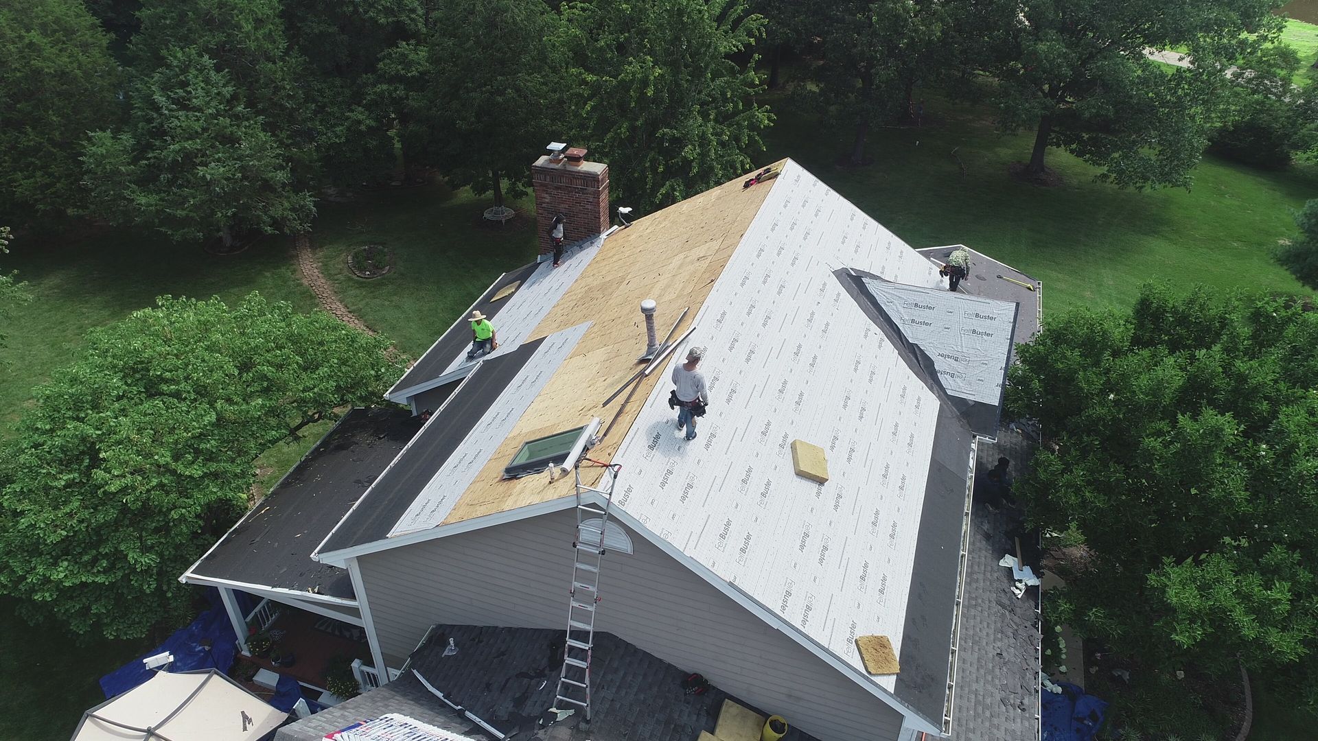 A man wearing yellow gloves is cleaning a gutter on a roof.